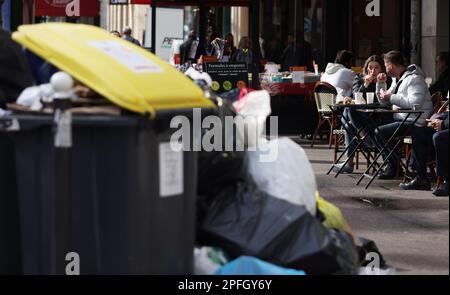 Parigi, Francia. 17th Mar, 2023. La gente ha caffè accanto ai bidoni pieni di rifiuti a sinistra sulla strada del centro di Parigi, Francia, 17 marzo 2023. È probabile che i rifiuti continuino ad accumularsi nella capitale, poiché i raccoglitori di rifiuti e i pulitori di strada saranno in sciopero fino a marzo 20. Credit: Gao Jing/Xinhua/Alamy Live News Foto Stock