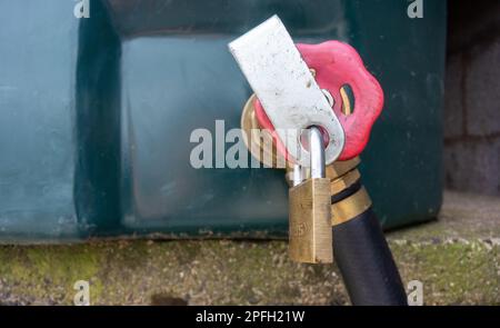 Lucchetto su un serbatoio diesel rosso in un cortile per prevenire i furti. North Yorkshire, Regno Unito. Foto Stock