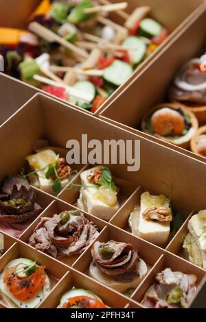 antipasti serviti in una scatola per il catering in un locale. Spuntini gourmet preparati con deliziosi ingredienti a base di carne, pesce e formaggio Foto Stock