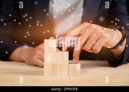 Un uomo d'affari con le dita che si arrampicano su una scala da cubetti di legno sul tavolo Foto Stock