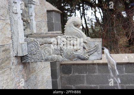 Rubinetto d'acqua in stile antico costituito da pietra naturale con un bellissimo design architettonico situato all'esterno del tempio Foto Stock