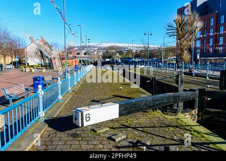 Serratura 6 sul canale Huddersfield a Piazza Armentieres, Stalybridge, Tameside, Manchester, Inghilterra, REGNO UNITO. Neve coperta Wild Bank Hill in lontananza. Foto Stock