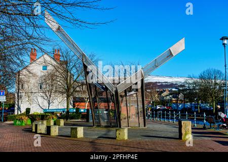 Lockgates Sundial, una scultura di Alan Dawson, Piazza Armentieres, Stalybridge, Tameside, Manchester, Inghilterra, Regno Unito. Wild Bank Hill in lontananza. Foto Stock