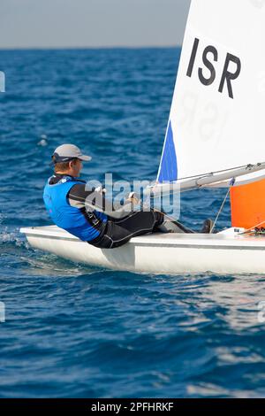 Foto di un adolescente che naviga in barca a vela di classe laser intorno a una boa arancione Foto Stock