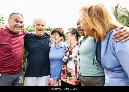 Gruppo di diversi amici anziani che si divertono dopo una sessione di allenamento al parco Foto Stock