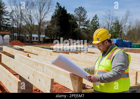 Ingegnere edilizio con una vasta esperienza che tiene in mano il progetto BluePrint che monitora i progressi della costruzione mentre si verifica Foto Stock