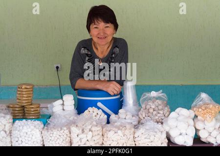 Donna kazaka dietro il suo stand con formaggio di capra e kumis, Parco Nazionale di Altyn Emel, Provincia di Almaty, Kazakistan, Asia Centrale, solo per uso editoriale Foto Stock