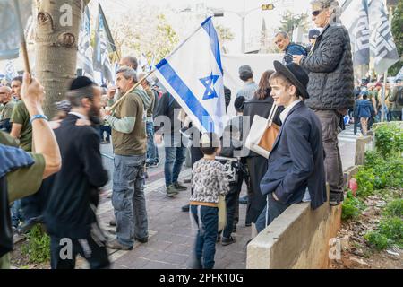 Bnei Brak, Israele. 16th Mar, 2023. I residenti ultra ortodossi di Bnei Brak camminano accanto a una protesta dei soldati della riserva israeliana contro la riforma giudiziaria. I soldati hanno aperto un “centro di reclutamento” al servizio militare IDF in un atto di protesta contro la revisione giudiziaria nella città ultra-ortodossa di Bnei Brak. Credit: SOPA Images Limited/Alamy Live News Foto Stock