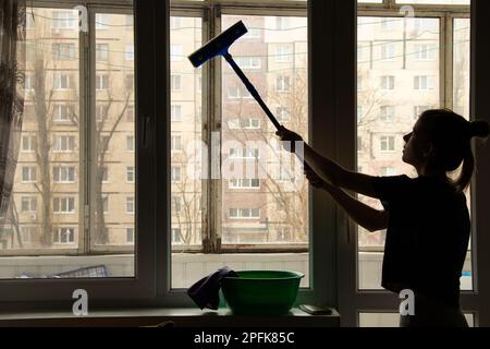 La ragazza lava la finestra dell'appartamento, pulendo Foto Stock