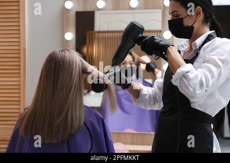 Stilista professionista che lavora con il cliente in salone di bellezza. Servizi di parrucchiere durante la quarantena di Coronavirus Foto Stock