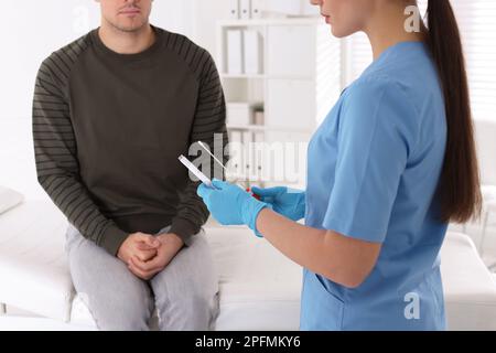 Medico che preleva il campione per il test STD dall'uomo in clinica, primo piano Foto Stock