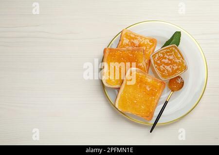 Deliziosi toast con marmellata serviti su un tavolo di legno bianco, vista dall'alto. Spazio per il testo Foto Stock