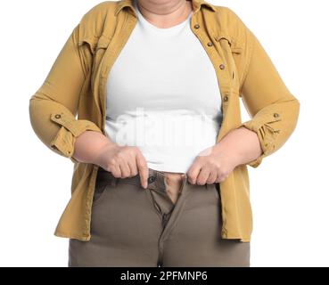 Donna sovrappeso cercando di buttare su pantaloni stretti su sfondo bianco, primo piano Foto Stock