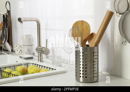 Supporto con utensili da cucina vicino al lavello sul piano cucina Foto Stock