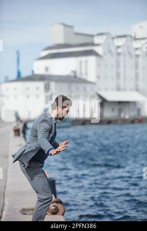 Posso solo uscire. un bel giovane uomo d'affari in piedi sul molo e che vuole saltare in acqua. Foto Stock