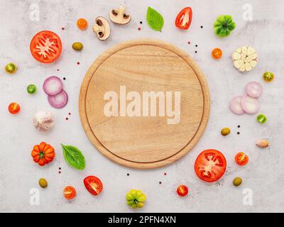 Gli ingredienti per la pizza fatta in casa sono allestiti su fondo di cemento bianco. Foto Stock