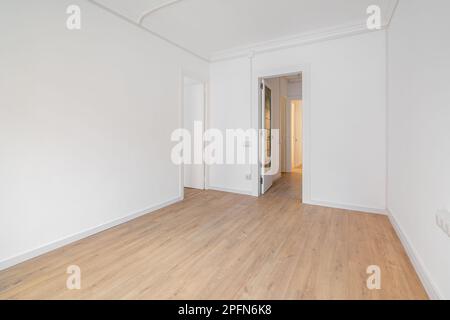 Camera bianca vuota con pavimento in laminato di legno e una porta aperta in casa nuova. Concetto di preparazione dei locali per l'occupazione e la realizzazione Foto Stock