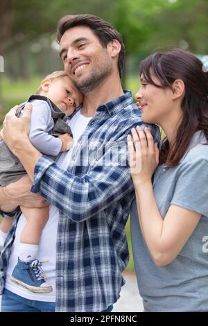 genitori orgogliosi tenendo la figlia del bambino in giardino Foto Stock