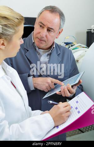 ingegnere che tiene in mano l'apprendista femminile di formazione tablet con gli appunti Foto Stock