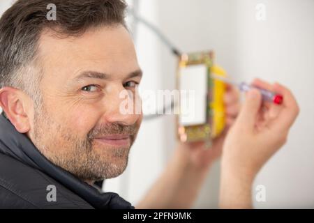 elettricista felice che ripara un dispositivo Foto Stock