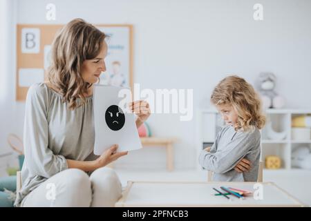 Giovane terapeuta della scuola che lavora con il bambino triste e le sue emozioni Foto Stock