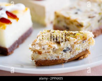 Piatto bianco pieno di dolci diversi. Gustosi dessert con farcitura, pistacchi. Foto Stock