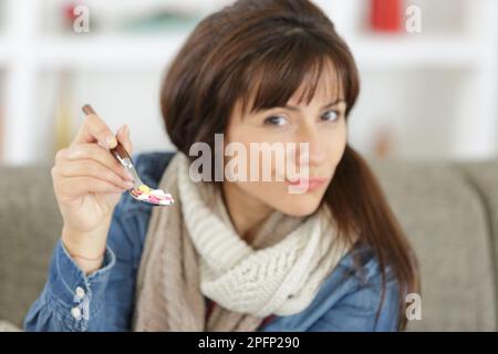 donna non assicurata tiene fuori le capsule sul cucchiaio Foto Stock