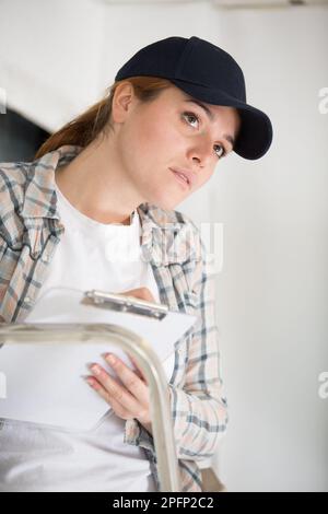 lavoratore femminile che prende appunti sulla scala Foto Stock