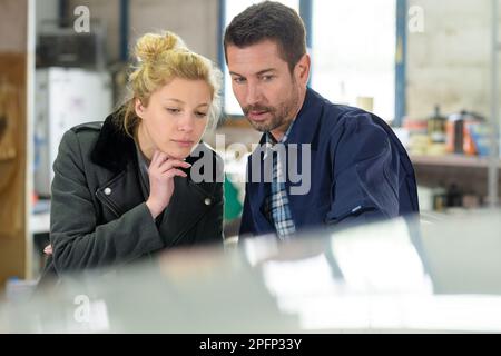 donna e uomo che guardano qualcosa in officina Foto Stock