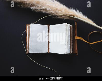 Diario o diario in pelle d'epoca su un tavolo nero con una bussola accanto Foto Stock
