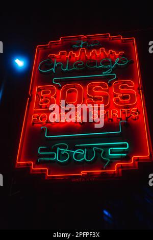 Un segno luminoso al neon 'Boss' montato su un edificio in mattoni che fa pubblicità a un bar Foto Stock