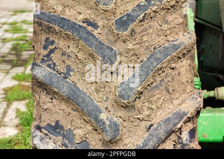 Pneumatico sporco di un trattore di grandi dimensioni coperto di fango dopo l'aratura sul campo Foto Stock