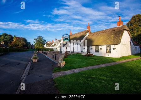 Il villaggio di etal con il suo bianco dipinto Bull pub nero l'unico pub in paglia a Northumberland, Inghilterra, Foto Stock