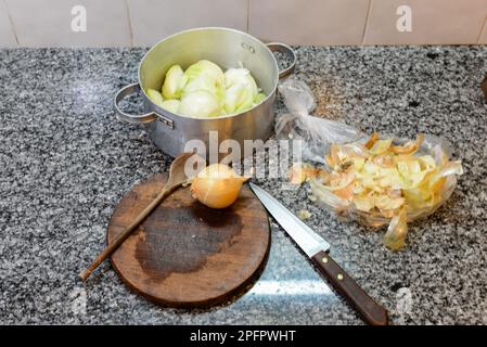 Preparazione degli articoli per la cottura di una crostata di cipolla come cucchiaio di legno, un coltello e una cipolla. Foto Stock