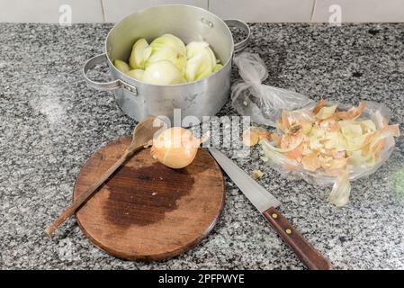 Preparazione degli articoli per la cottura di una crostata di cipolla come cucchiaio di legno, un coltello e una cipolla. Foto Stock