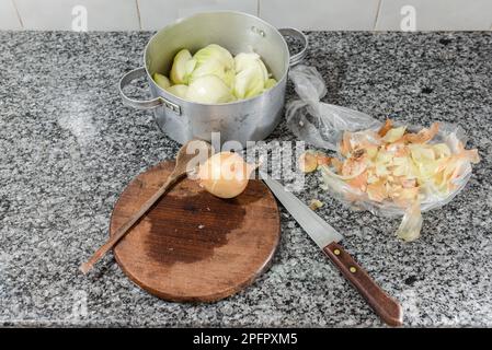 Preparazione degli articoli per la cottura di una crostata di cipolla come cucchiaio di legno, un coltello e una cipolla. Foto Stock