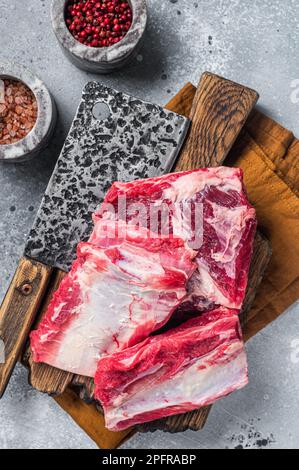 Costolette di vitello di manzo kalbi, carne cruda su polpetta di legno. Sfondo grigio. Vista dall'alto. Foto Stock