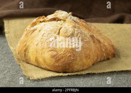 Una pagnotta di pane appena sfornato su un asciugamano. Pane fatto in casa delizioso e sano. Vista laterale Foto Stock