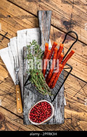 Piccole e sottili salsicce di kabanos fatte in casa in un cestino. Sfondo di legno. Vista dall'alto. Foto Stock