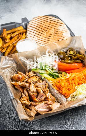 Doner kebab Shawarma su un piatto con patatine fritte e insalata in scatola per andare, da asporto. Sfondo bianco. Vista dall'alto. Foto Stock