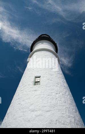 Vista prospettica bassa di un faro che si erge sulla costa rocciosa del mare. Foto Stock