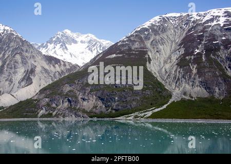 La vista primaverile delle alte montagne e dell'acqua calma con il ghiaccio nel parco nazionale di Glacier Bay (Alaska). Foto Stock