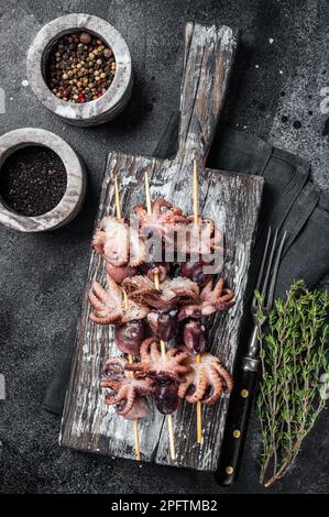Spiedini con mini polpi alla griglia. Sfondo nero. Vista dall'alto. Foto Stock