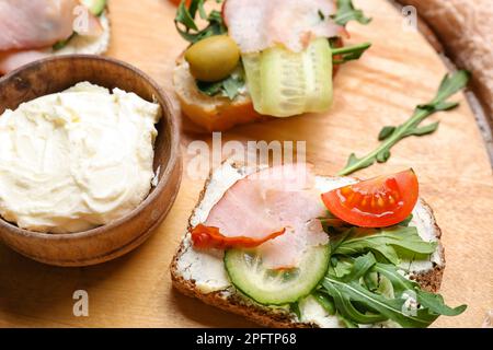 Tavola di legno con deliziosi panini e formaggio spalmabile, primo piano Foto Stock