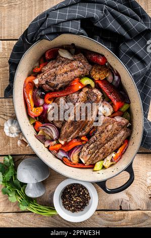 Stinco di agnello cotto a fuoco lento arrosto con verdure ed erbe aromatiche. Sfondo di legno. Vista dall'alto. Foto Stock