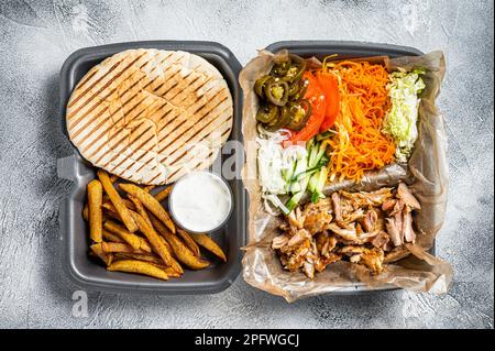 Doner kebab Shawarma su un piatto con patatine fritte e insalata in scatola per andare, da asporto. Sfondo bianco. Vista dall'alto. Foto Stock