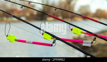 L'allarme morso si blocca su una canna da pesca contro lo sfondo dell'acqua. Canna da pesca mentre la pesca sul lago, fiume. Attrezzatura da pesca. Asta di carpa su una sta Foto Stock