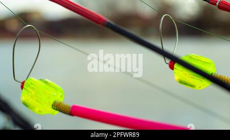 L'allarme morso si blocca su una canna da pesca contro lo sfondo dell'acqua. Canna da pesca mentre la pesca sul lago, fiume. Attrezzatura da pesca. Asta di carpa su una sta Foto Stock