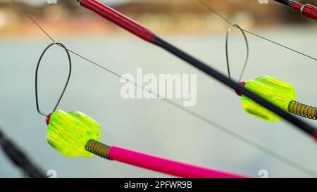 L'allarme morso si blocca su una canna da pesca contro lo sfondo dell'acqua. Canna da pesca mentre la pesca sul lago, fiume. Attrezzatura da pesca. Asta di carpa su una sta Foto Stock