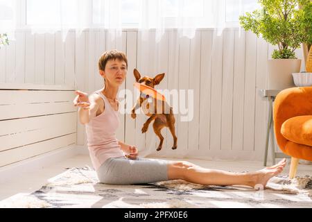 Donna che pratica l'esercizio con il cane a godere e rilassarsi con yoga. Trascorri del tempo e gioca con il tuo cane a casa. Resto amore per il concetto di cane Foto Stock